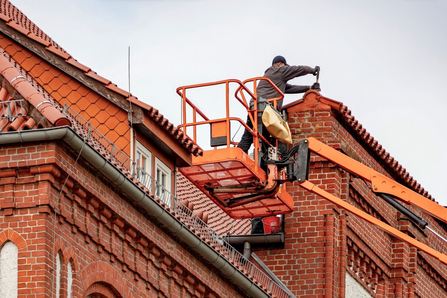 Roofer working from a lift on a red brick building