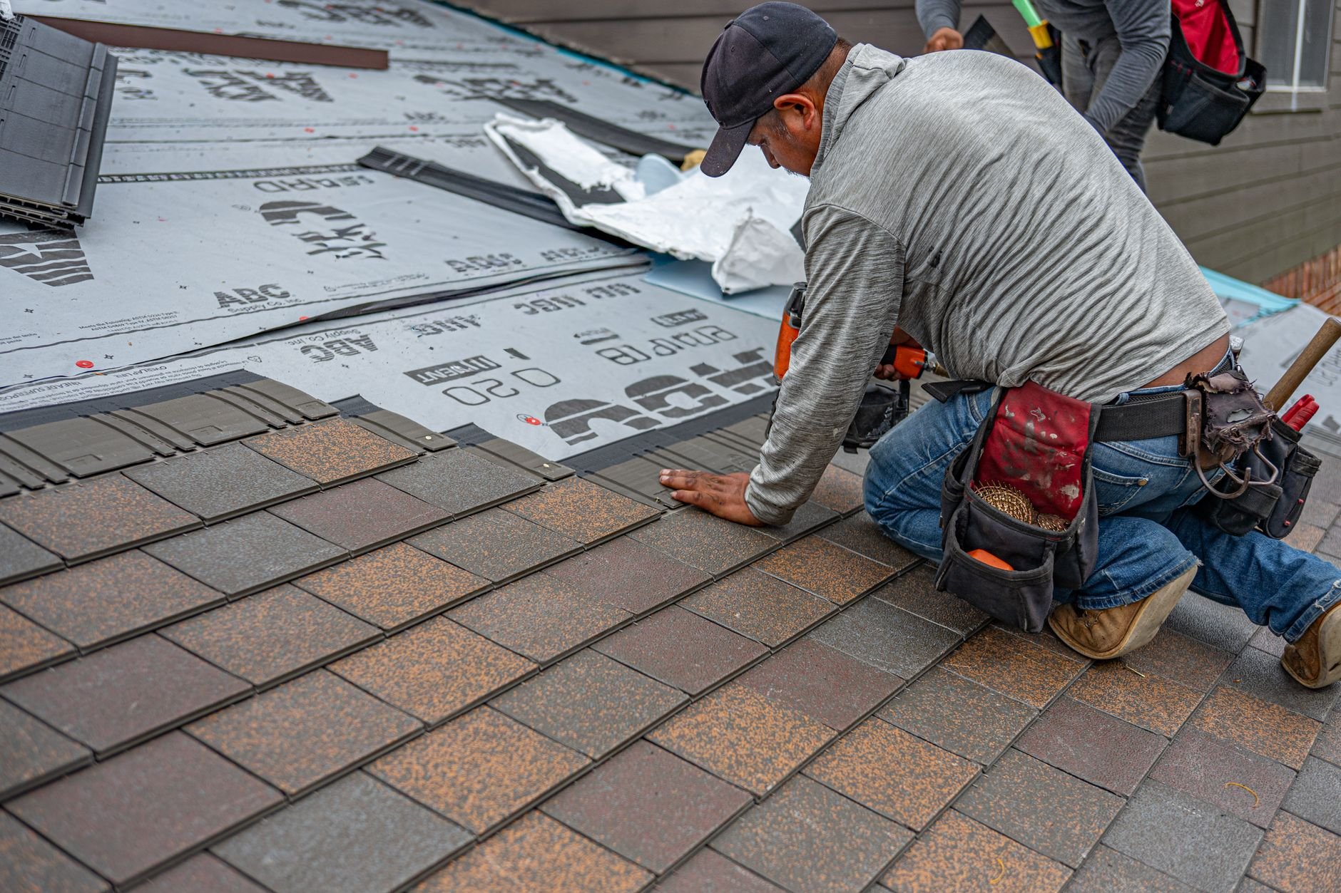 Skilled roofer installing asphalt shingles on a home
