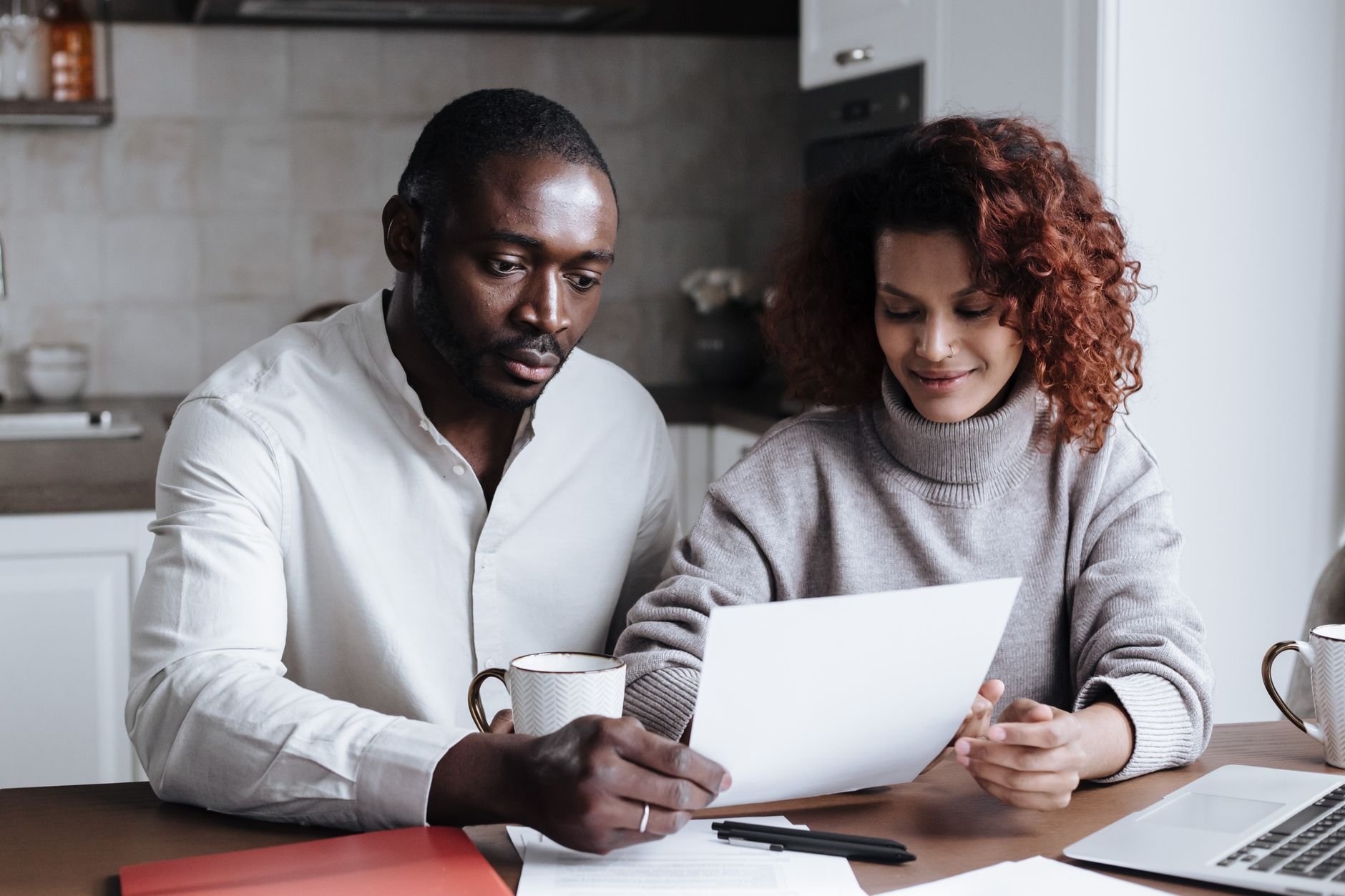 A couple reviewing paperwork at a kitchen table